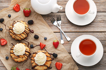 Delicious bundt cakes with berries and cup of tea on grey wooden table