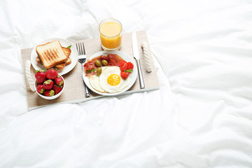 Tasty breakfast in bed on wooden tray