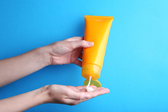 Female Hand Holding Sunscreen Cream On Blue Background