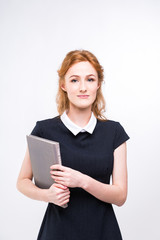 Beautiful girl with red hair and gray book in hands dressed in black dress on white isolated background