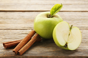 Ripe green apples with cinnamon on grey wooden table