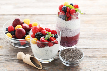 Chia pudding with berries in glasses on grey wooden table