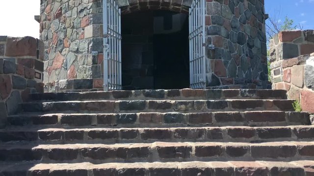 Old stone tower where clip starts at the steps and slowly pans upwards to the top before finally reaching a partly cloudy blue sky above.