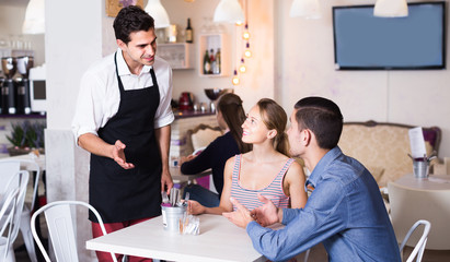 Smiling couple guests giving order to welcoming waiter