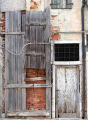 abandoned board up derelict house with padlocked door and decaying brick walls in italy