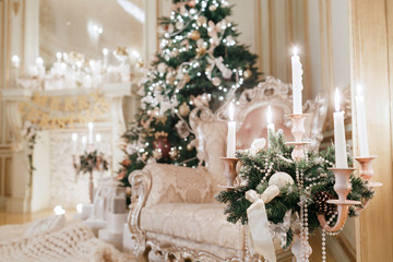 the chandelier with candles in the foreground. Christmas evening. classic apartments with a white fireplace.