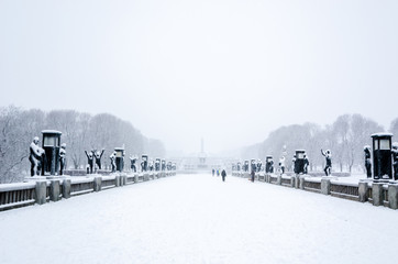 OSLO, January 2015. Some people walking during a snow fall in Vigeland sculpture park or Vigelandpark in Oslo, Norway. Vigeland is located in the Frognerpark in Oslo - obrazy, fototapety, plakaty