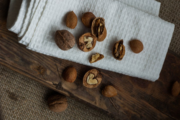 A lot of walnuts on a white towel on a wooden background.