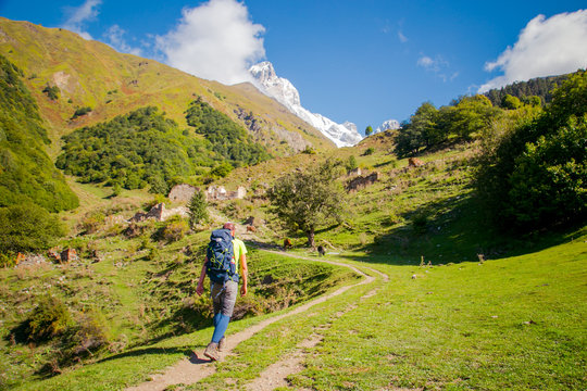 Young men going in the mountains. View to the snowy mountain peaks Ushba .covered by a glacier.  Ushba in Caucasus Mountains, Svaneti, Geogria.
