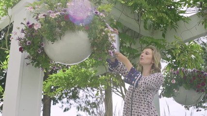 Young woman pouring water onto flowers