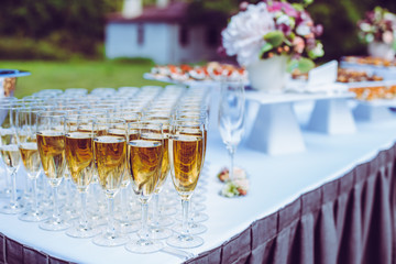 Wedding snack and champagne table at the church after wedding ceremony.  Champagne in glasse in background snacks. Elegant Fade colors. Vintage color effect.