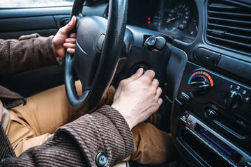 Man driver hand puts car key to keyhole to start his automobile