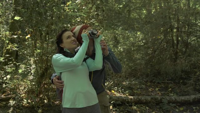 A mid adult couple taking photographs in a forest