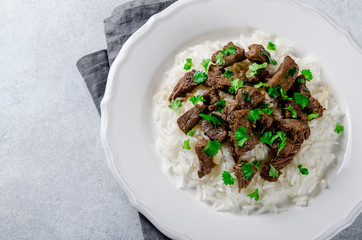 Cooked rice and fried beef with parsley served in white plate on