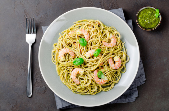 Spaghetti with fried prawns and pesto sauce in a gray plate, dar