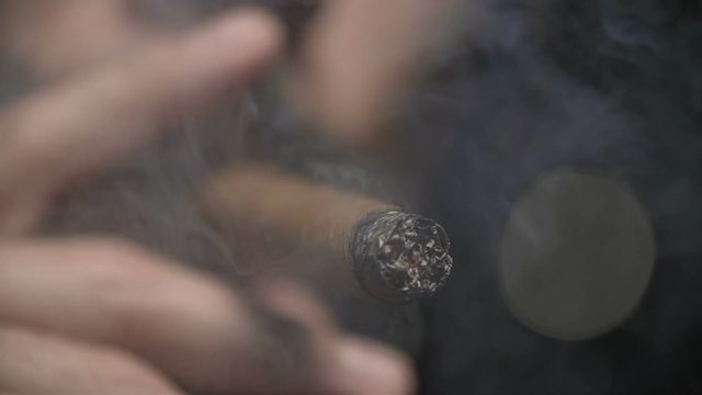 Close Up Man Smoking Cigar Slow Motion. a close up view of the end of a cigar burning with the inhales and smoke in slow motion