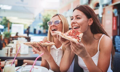 Foto op Plexiglas Pizzeria Pizza tijd. Jonge meisjes die pizza eten in een café. Consumentisme, levensstijl