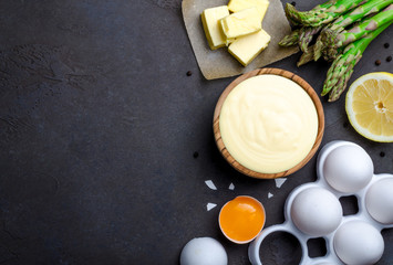 Basic french sauce hollandaise in a wooden bowl with ingredients