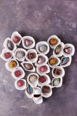 Colored chocolate candies. Creative candy in the shape of a heart on a gray background. St.Valentine's Day concept