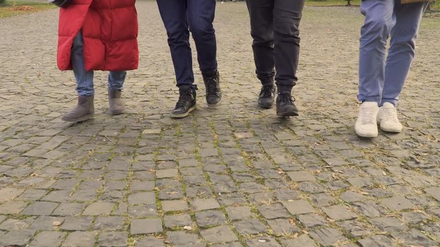 Legs of four people walking