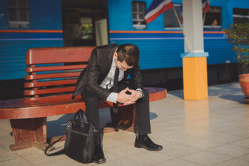 Fototapeta premium Young asian businessman feel stressed/worry/headache/disappoint during working while sit at train station, vintage photo and film style.