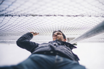 Young boy holds a metal fence.