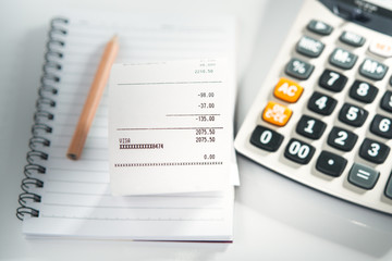 Grocery shopping list on notebook with calculator and pencil - money account management concept