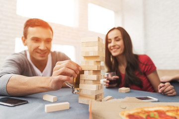 Fototapeta premium The company of young people plays a table game called jenga.