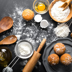Baking ingredients. Bowl, eggs, flour, eggbeater, rolling pin and eggshells on black chalkboard from above.