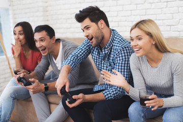 Fototapeta premium Two guys and two girls play on the game console.