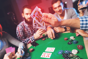 Young people play poker at the table. - obrazy, fototapety, plakaty