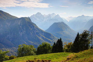 Steep forested walls of Vrata, Kot and Sava valleys with Jerebikovec, Rjavina and Triglav peaks, Triglav National Park, Julian Alps sunny autumn morning from grassy glade of Karavanke range Slovenia