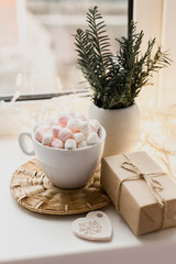Cup of hot chocolate and marshmallow in the background of Christmas decorations.