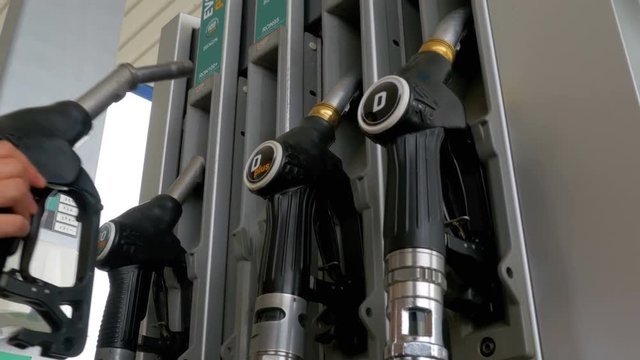Woman hand using fuel nozzles at a gas station. Gasoline or petrol station gas fuel pump nozzle. Filling station. Various pistols for fuel at the gas station. Different Gasoline gun at a petrol