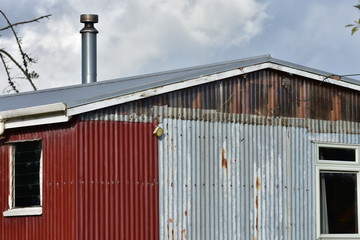 Shed made from partially rusty corrugated sheet metal panels.