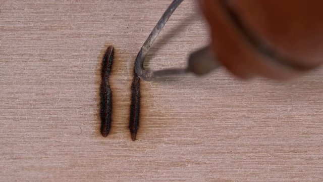 a soldering iron on wood,man burns patterns and symbols
