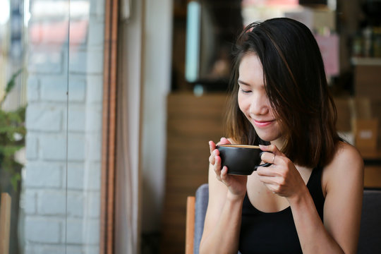 A beautiful woman and hot coffee of latte art cup before drinking in loft cafe