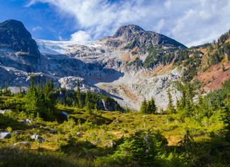 Hiking to the highest peak surrounded by meadows and lakes in the high alpine mountains of British Columbia