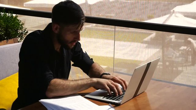 Copywriter typing text on laptop at cafe table.