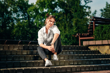 Fototapeta premium Beautiful girl in a white tank top in the park, sexy look