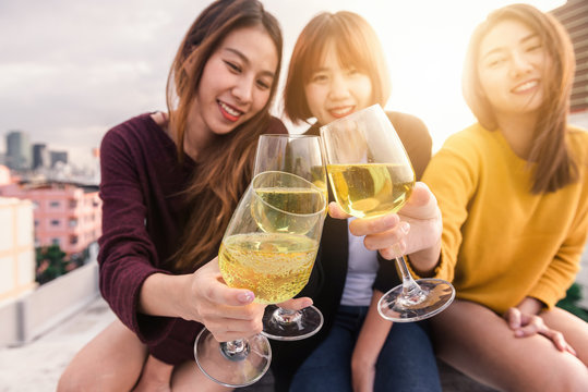 Outdoor shot of young people toasting drinks at a rooftop party. Young asian girl friends hanging out with drinks. Holiday celebration festive party. Teenage lifestyle party. Freedom and fun outdoor.