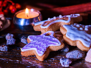 Candle light table with Christmas gingerbread cookies and cinnamon stick and star sweets are on wooden table and burning candles. Xmas still life object.