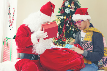 Santa Claus and the young boy with gift boxes. Miracles on Christmas.