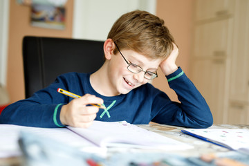 Naklejka na ściany i meble Happy school kid boy at home making homework