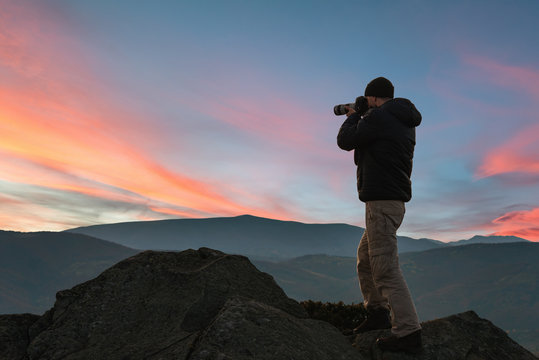 Man taking picture of beautiful sunset in mountains