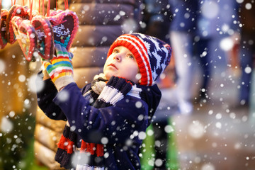 Little cute kid boy buying sweets from a cancy stand on Christmas market