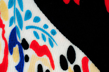 Synthetic knitted fabric, white and black background. The flowers are red and blue. A red and blue...