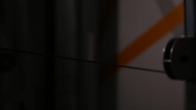 Close-up, hands holding the rowing simulator, relief muscular back. Pull the lower unit sitting. Trainer back in the gym.