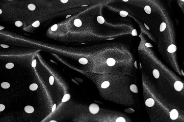 Texture, background, pattern. Girl's skirt. Silk fabric on a black background white polka dots