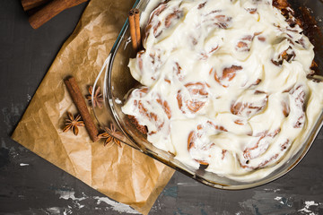 Fresh cinnamon buns with cream cheese in gass bowl on the rustic wooden background